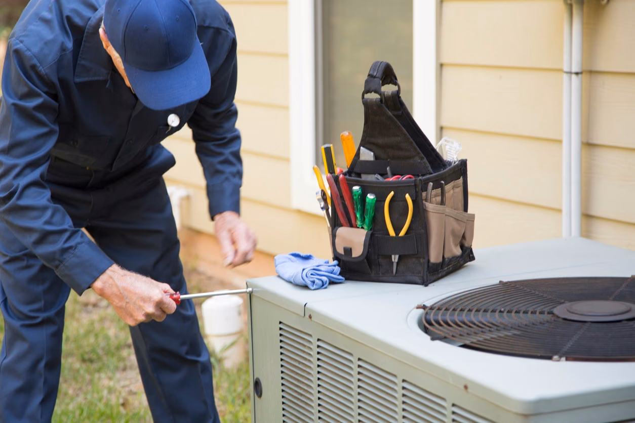 AAERO technician inspecting and servicing an outdoor AC condenser unit on a residential AC repair visit in Marin County